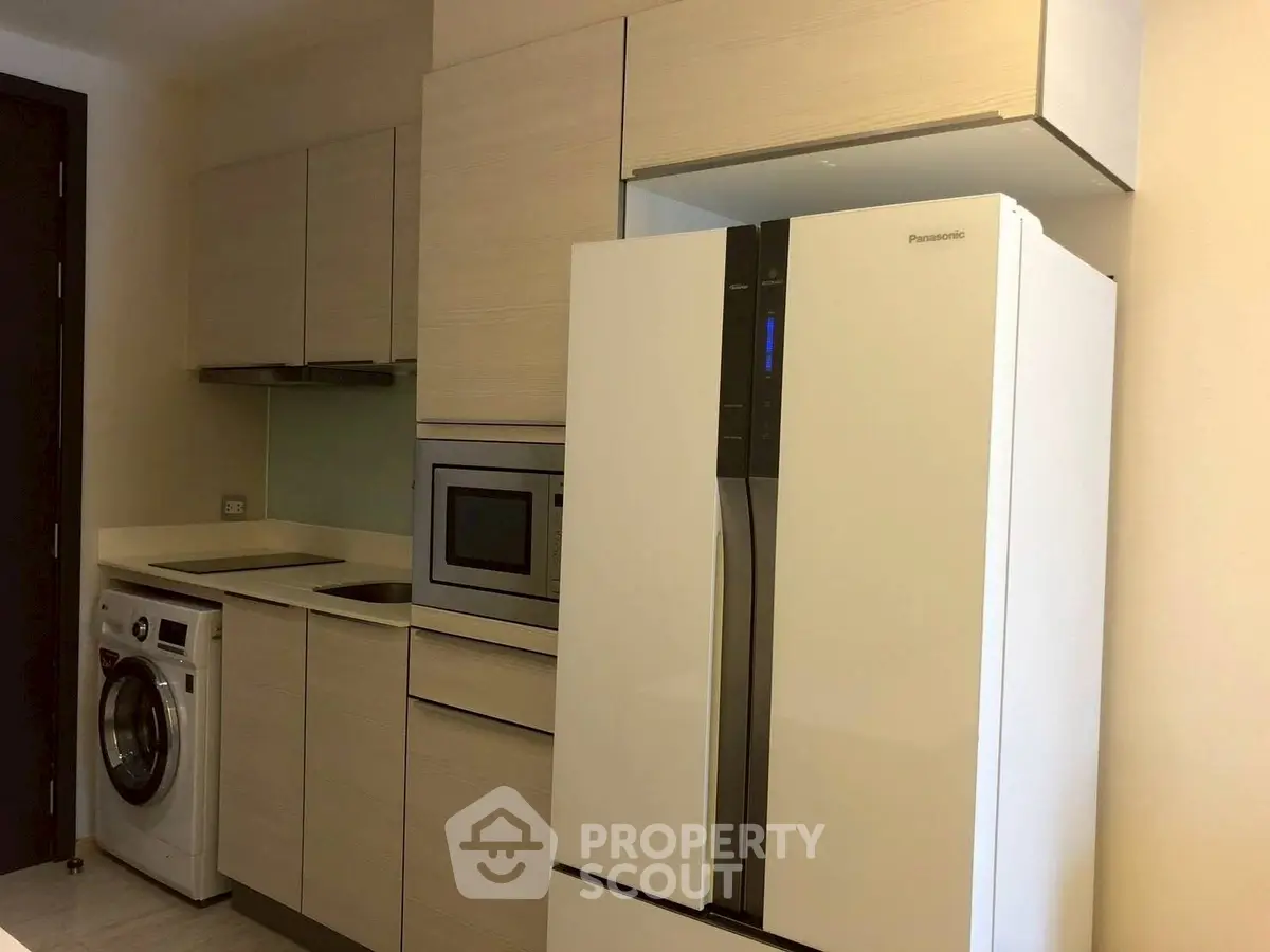 Modern kitchen with sleek appliances including fridge, oven, and washing machine.