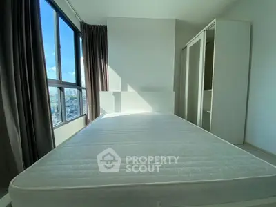 Bright and spacious bedroom with large window and modern wardrobe in a high-rise apartment.