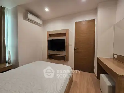 Modern bedroom with sleek wooden furniture and wall-mounted TV in a cozy apartment.
