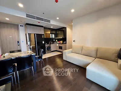 Modern living room with open kitchen, featuring sleek furniture and hardwood floors in a stylish apartment.