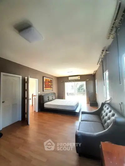 Spacious bedroom with modern decor and large windows for natural light.