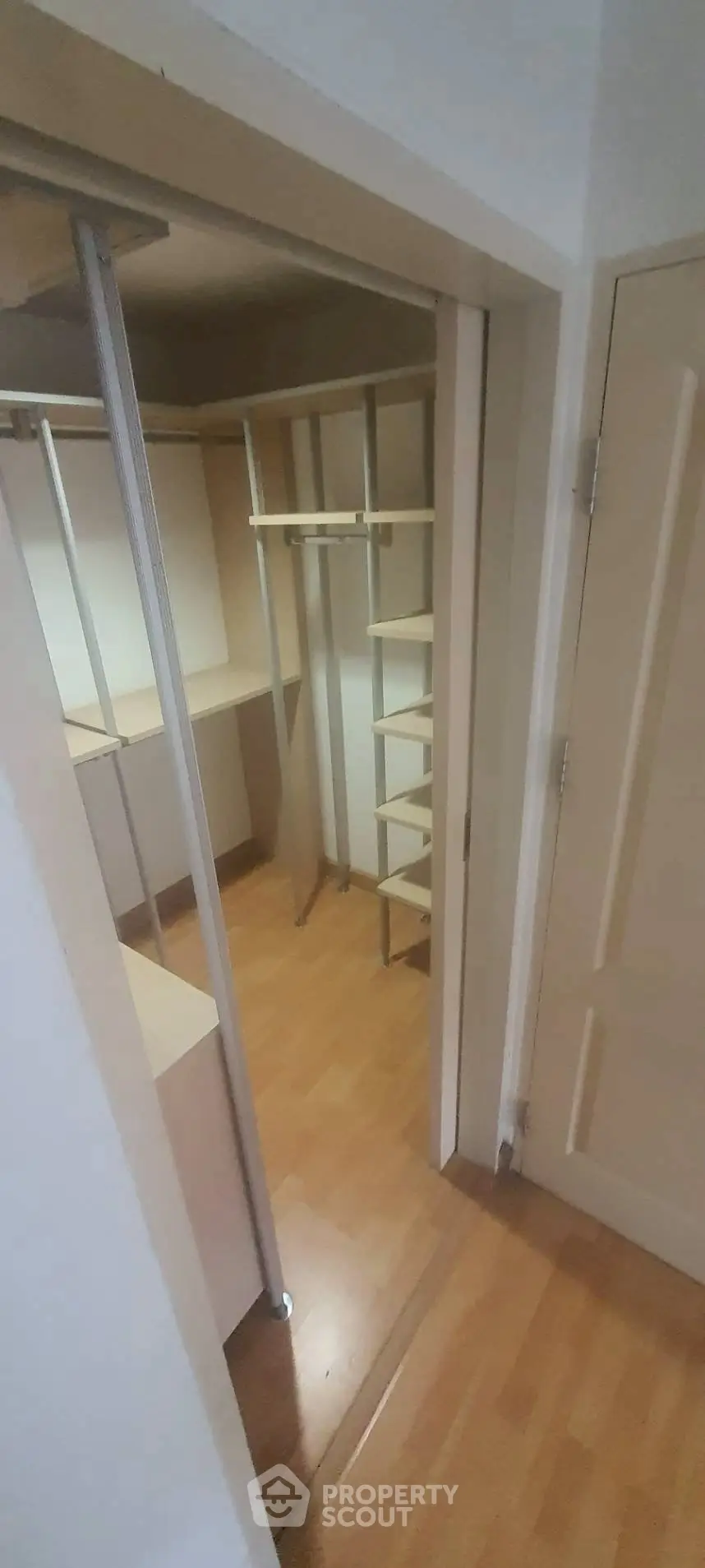 Spacious walk-in closet with wooden flooring and ample shelving space.