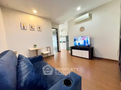 Cozy living room with blue sofa and wall-mounted TV, perfect for relaxation.