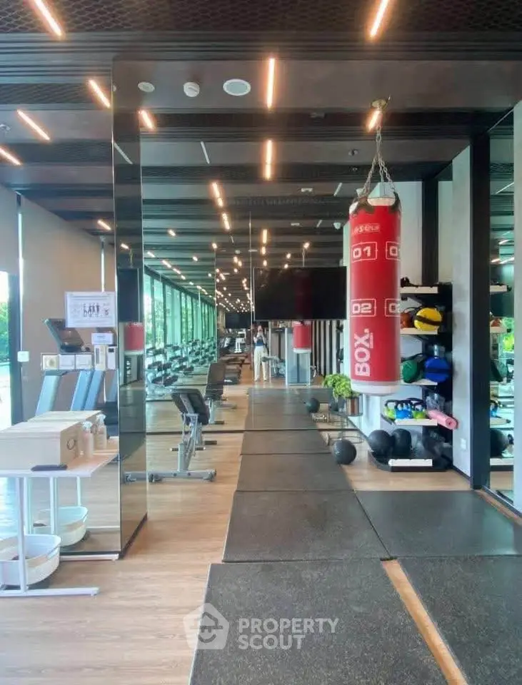 Modern gym with boxing equipment and large mirrors in luxury residential building.