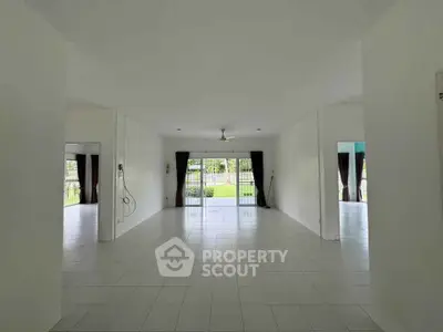 Spacious open-plan living room with large windows overlooking a lush garden, perfect for family gatherings.