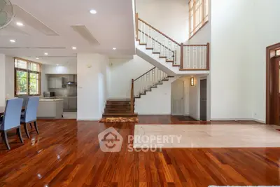 Spacious open-plan living area with elegant staircase and polished wooden floors