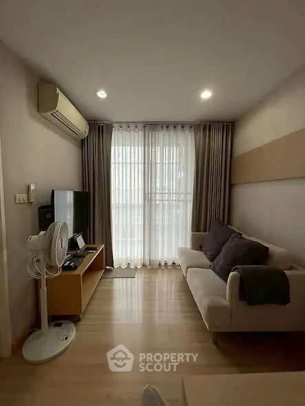 Cozy living room with modern decor, featuring a comfortable sofa, TV, and large window with curtains.