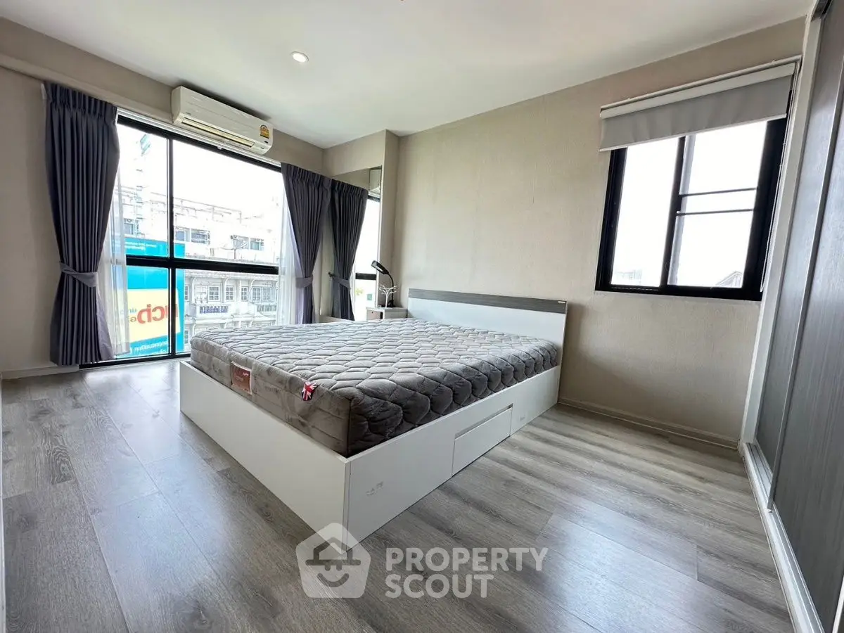 Spacious bedroom with modern decor and large windows offering city views.