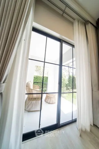 Bright and airy living room with large glass doors opening to a lush garden view.