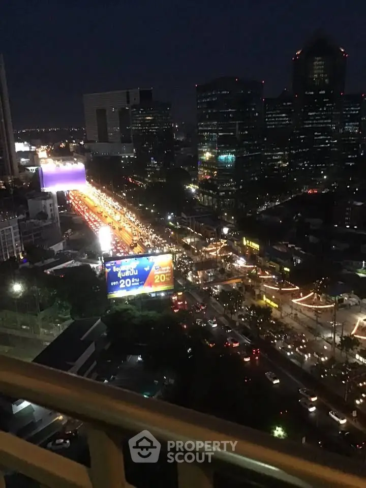 Stunning cityscape view from a high-rise balcony at night, showcasing vibrant city lights and bustling streets.