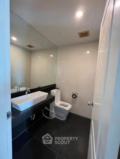 Modern bathroom with sleek fixtures and large mirror in contemporary home.