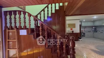 Charming wooden staircase leading to a cozy kitchen with classic cabinetry and tiled flooring.