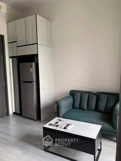 Modern compact living room with sleek furniture and integrated kitchen appliances.