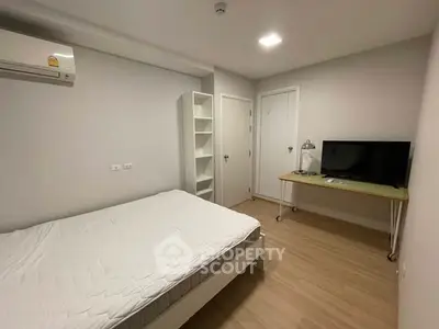 Modern bedroom with minimalist design, featuring a comfortable bed, air conditioning, and a sleek TV setup.