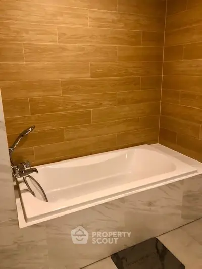 Modern bathroom with elegant bathtub and wood-style wall tiles