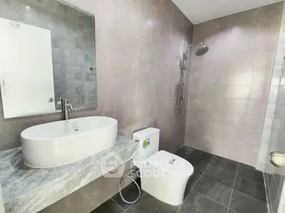 Modern bathroom with sleek design featuring a large mirror, elegant sink, and spacious shower area.