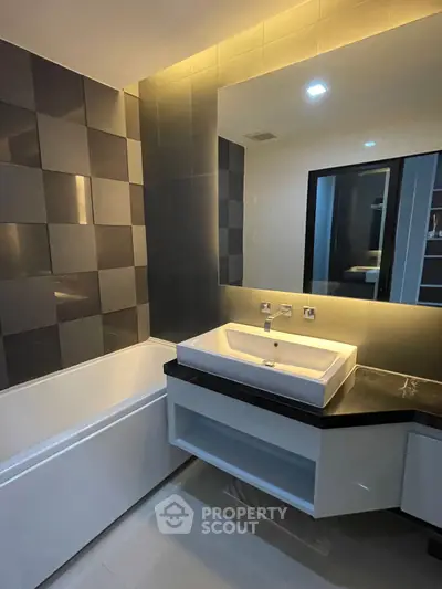 Modern bathroom with sleek design, featuring a large mirror and stylish sink.