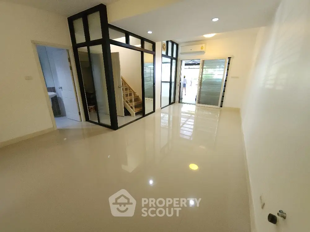 Spacious modern living room with glossy floors and glass partition