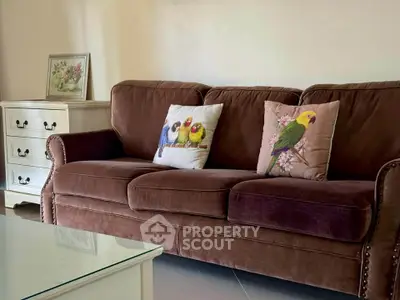 Cozy living room with plush brown sofa and decorative bird-themed cushions, perfect for relaxation.