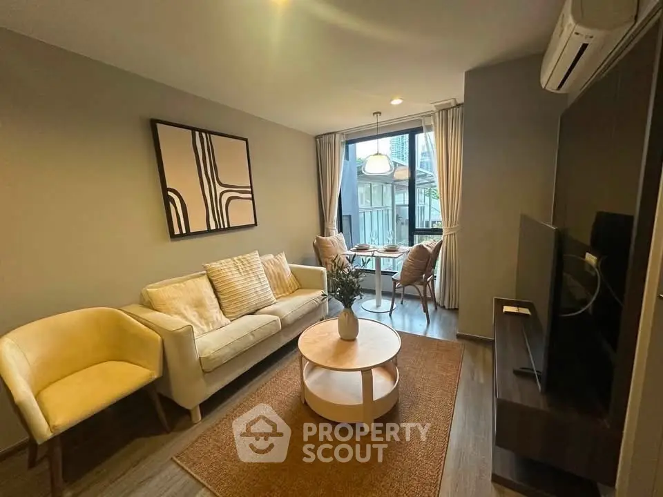 Stylish modern living room with cozy seating and large window view.