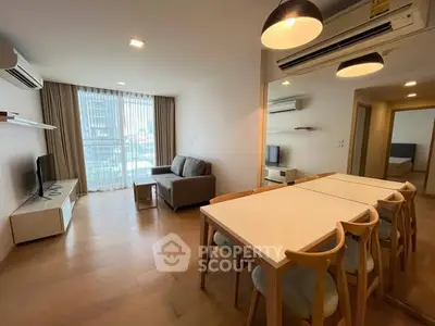 Modern living room with dining area, large windows, and stylish furniture in a bright apartment.
