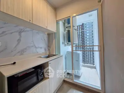 Modern kitchen with sleek cabinetry and adjacent laundry area in high-rise apartment.