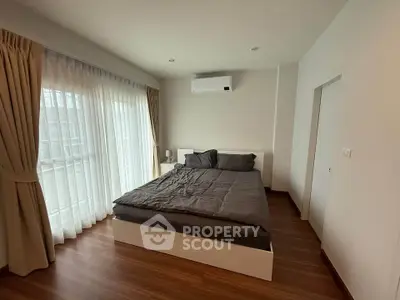 Modern bedroom with large windows and elegant curtains in a cozy apartment.