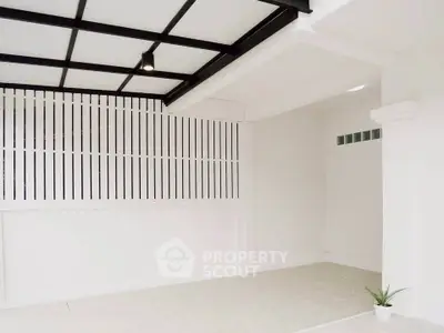 Modern minimalist interior space with white walls and tiled floor, featuring a small potted plant.