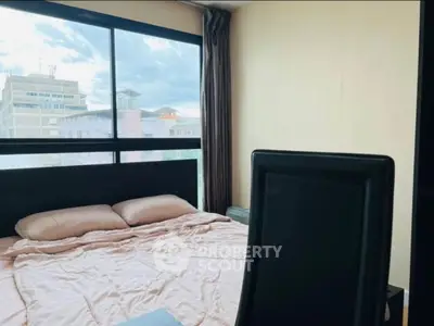 Cozy bedroom with large window offering city views, perfect for urban living.