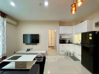 Modern living room with open kitchen, featuring sleek appliances and stylish lighting.