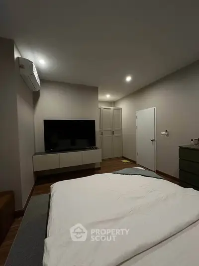 Modern bedroom with sleek design, featuring a wall-mounted TV and stylish furniture.