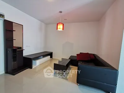 Modern living room with sleek black furniture and stylish red accents.