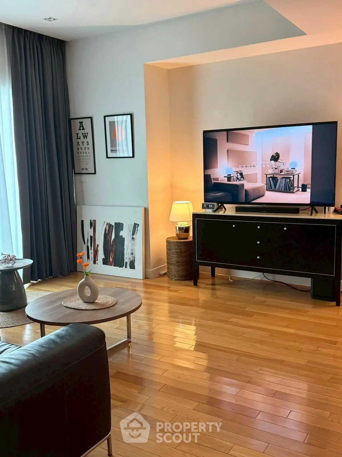 Stylish living room with modern decor, hardwood floors, and large TV setup.
