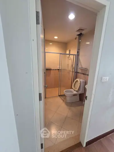 Modern bathroom with glass shower enclosure and tiled walls in a contemporary apartment.
