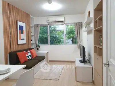 Modern living room with stylish decor, large window, and cozy seating area in a compact apartment.