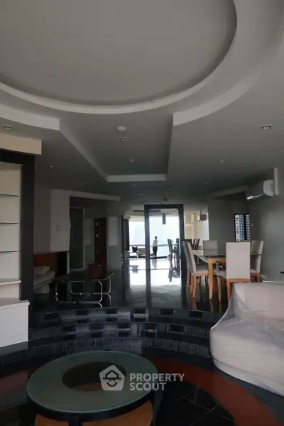 Spacious modern living room with elegant dining area and stylish ceiling design.