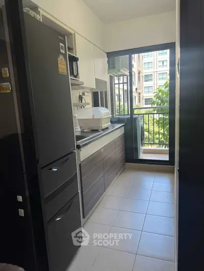 Modern kitchen with sleek cabinets and balcony view in urban apartment