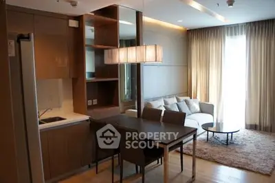 Modern living room with open kitchen, cozy seating, and elegant lighting