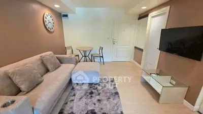 Cozy living room with modern decor, plush sofa, wall-mounted TV, and stylish clock, perfect for relaxation.