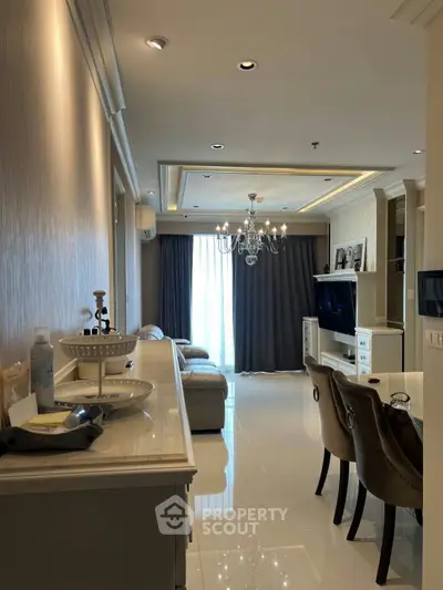 Elegant living room with chandelier and modern decor, featuring a cozy seating area and stylish dining space.