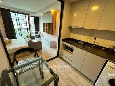 Modern studio apartment with open layout, featuring a cozy living area, sleek kitchen, and large windows for natural light.
