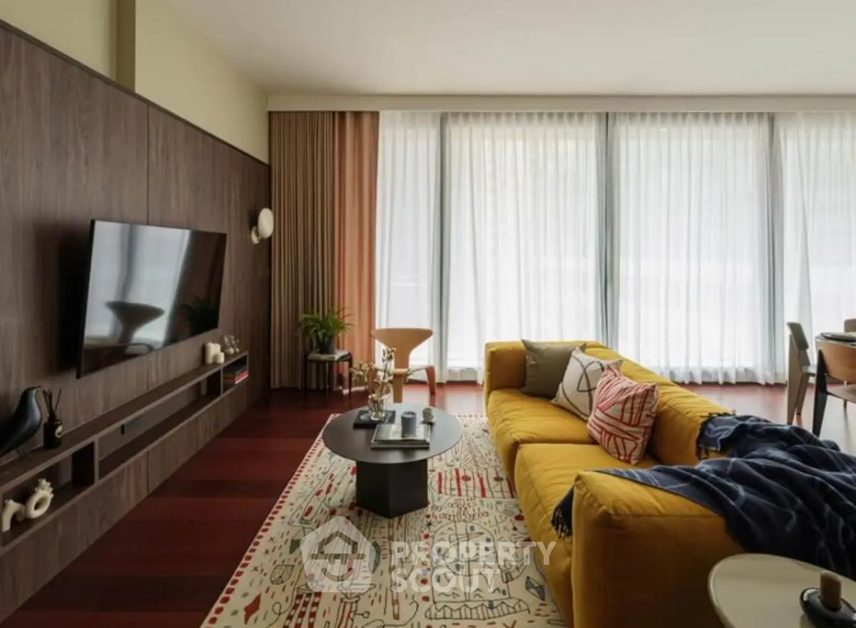 Spacious living room with modern decor, featuring a vibrant yellow sofa and large windows with sheer curtains.