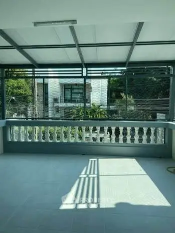 Spacious balcony with modern railing and scenic view of greenery and buildings.