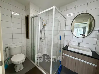 Modern bathroom with glass shower and sleek vanity in contemporary home.