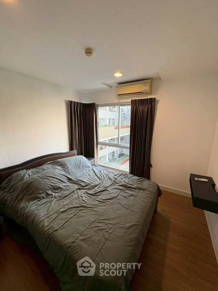 Cozy bedroom with large window and air conditioning in modern apartment.