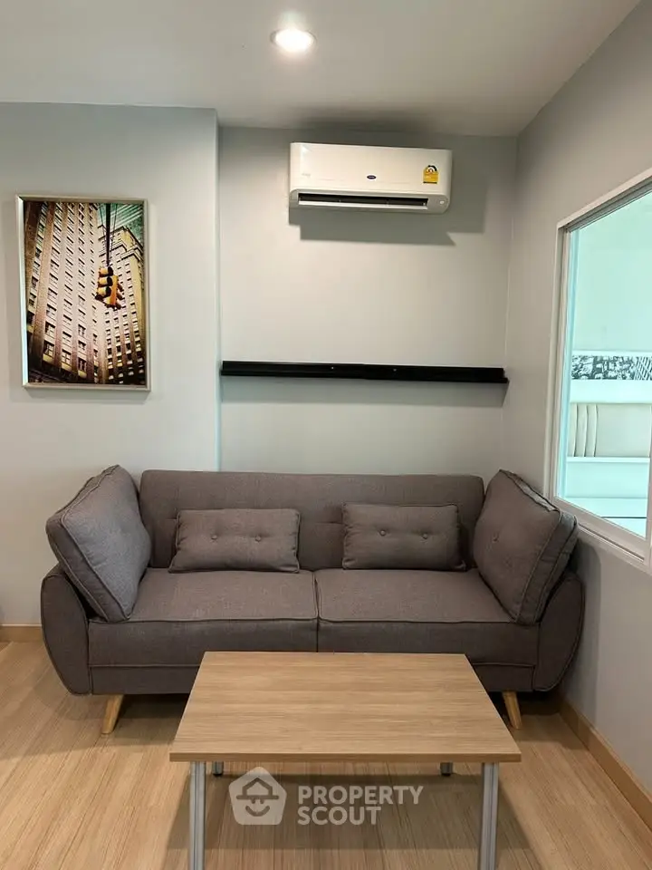 Modern living room with stylish gray sofa and wall-mounted air conditioner, perfect for cozy relaxation.