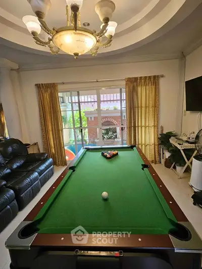 Luxurious living room with pool table and elegant chandelier, perfect for entertainment and relaxation.
