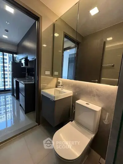 Modern bathroom with sleek fixtures and a view into a contemporary kitchen