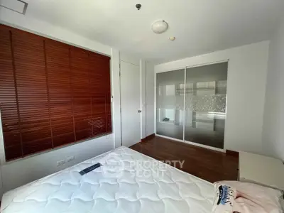 Spacious bedroom with wooden blinds and sliding closet doors, perfect for modern living.