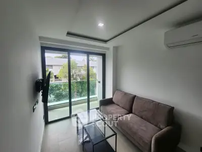 Modern living room with glass balcony, sleek sofa, and air conditioning, offering a serene view.